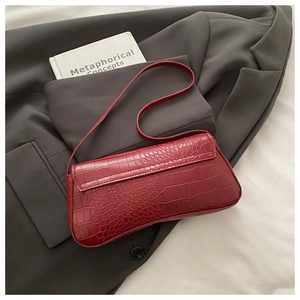 Detail of burgundy crocodile-embossed baguette bag on a grey blazer for office style