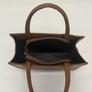 Brown leather tote bag featuring a spacious three-compartment interior and dual top handles