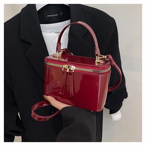 Detail of burgundy patent leather vanity case bag with gold zippers and top handle