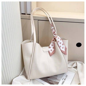 Detailed view of off-white tote bag with polka dot scarf on minimalist background