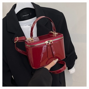 Close-up of wine red patent leather box bag with gold double zippers and top handle