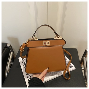 Detail of a brown structured handbag showing the golden lock and smooth leather texture