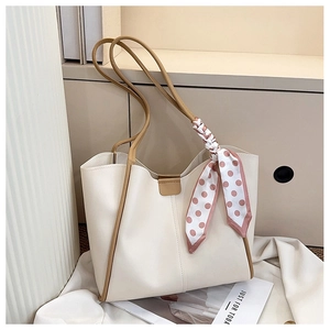 Detail of off-white tote bag featuring brown edge piping and a pink polka dot silk scarf