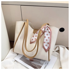 Close-up of cream tote bag with brown straps and elegant pink polka dot silk scarf detail