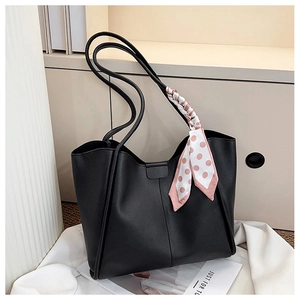 Detail of black leather tote bag with a pink polka dot scarf on a minimalist background