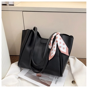 Detail of black pebbled leather tote bag with a polka dot silk scarf tied on the handle