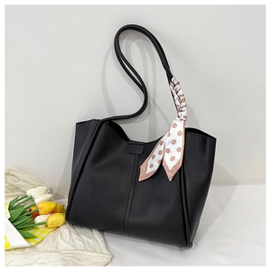 Detail of black leather tote bag with silk scarf on handle and decorative stitching