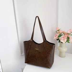 Brown oil-wax leather tote bag with shoulder straps on a clean minimalist background