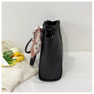 Detail of black leather tote bag featuring a decorative polka dot scarf and spacious base