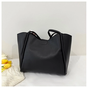 Detailed view of a black tote bag with decorative floral scarf handle and a wide wavy top