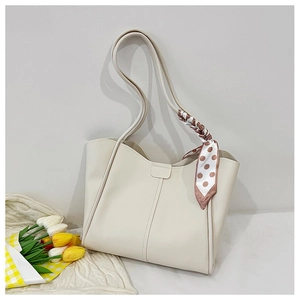 Detail of off-white leather tote bag with magnetic buckle and polka dot silk scarf