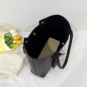 Large black leather tote bag with inner pouch and magnetic buckle in home setting