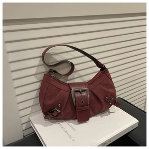 Dettaglio della borsa a mezzaluna rosso scuro con fibbia in metallo vintage su libri