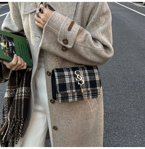 Close-up of black and white houndstooth crossbody bag with gold chain and S-logo tassel