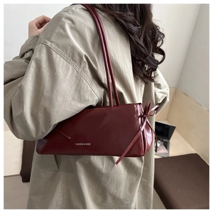 Dettaglio della borsa a spalla in pelle lucida bordeaux con fiocco laterale e logo argento