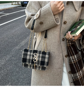 Detail of black and white checkered crossbody bag with gold chain and SSS buckle