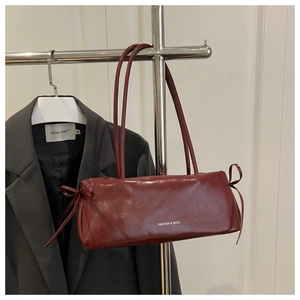 Detail of burgundy glossy underarm bag with decorative bow ties and slim shoulder strap
