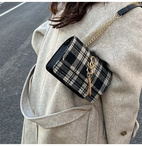 Detail of black and white plaid tweed bag featuring a gold S logo and tassel fringe
