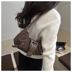 Dettaglio borsa a spalla vintage marrone scuro con cinghie e fibbie metalliche in scena