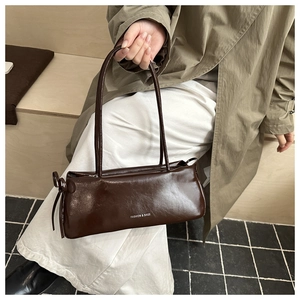 Detail of a brown leather shoulder bag featuring a side bow tie and Fashion text print