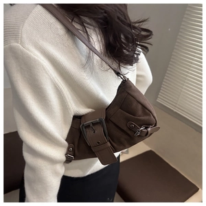 Macro detail of dark brown suede shoulder bag with decorative belt buckle and slim leather strap