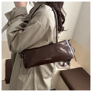 Detail of vintage dark brown baguette bag featuring side drawstring and glossy finish