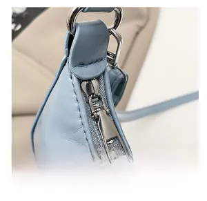 Detailed close-up of the smooth silver metal zipper on a light blue leather shoulder bag