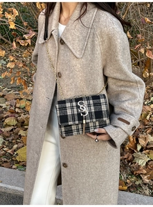 Detail of black and white plaid handbag featuring golden chain strap and fringe tassel