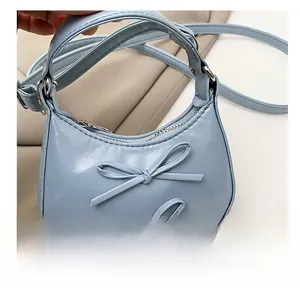 Close-up of light blue crescent mini handbag featuring decorative twin ribbon bows