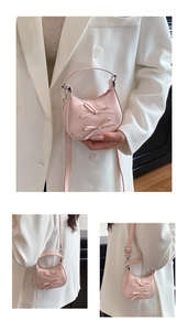Detail of pink crescent handbag featuring decorative bows and adjustable shoulder strap