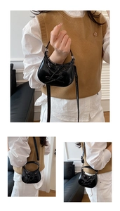 Detail of black glossy handbag with bow decoration and detachable shoulder strap