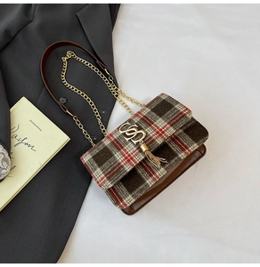 Macro detail of plaid tweed flap and gold metal fringe buckle on luxury leather bag