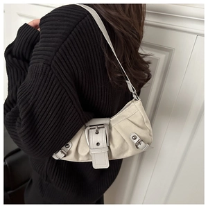 Detail of a creamy white pleated dumpling bag with vintage silver buckle on a model
