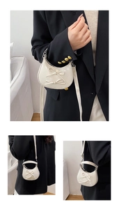 Detail of white mini crescent bag with double bow design and glossy finish
