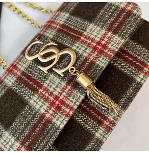 Detail of plaid chain bag featuring golden letter buckle and metallic tassel accents