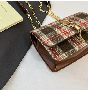 Close-up of vintage plaid shoulder bag featuring golden letter hardware and tassel detail