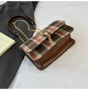 Detail of British plaid crossbody bag with gold chain strap and tassel hardware