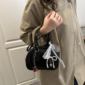 Borsa vintage nera con ciondoli a ciliegia e pizzo, indossata con trench