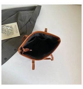 Internal view of brown tote bag with black lining, zipper pocket, and dual slot pockets