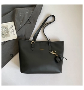 Detail van zwarte leren tote bag met gouden gesp, olifantenhanger en modieus logo