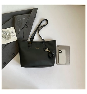 Detail of black leather tote bag with elephant pendant, gold logo and spacious interior