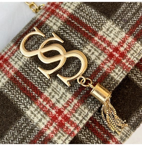 Close-up of checkered tweed handbag with gold interlocking logo and chain tassel detail