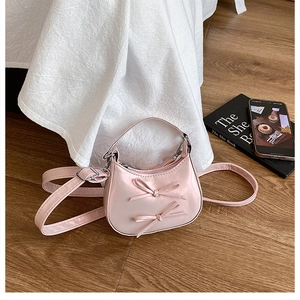 Detailed top view of light pink pearlescent crescent bag with bow accents and silver hardware
