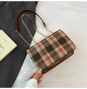 Detail of vintage plaid bag with chain strap and brown leather trim on textured fabric