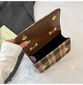 Detail view of plaid shoulder bag with inner brown flap and golden magnetic closure