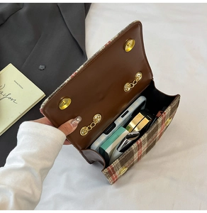 Macro detail of plaid tweed handbag interior with magnetic gold clasp and brown leather flap