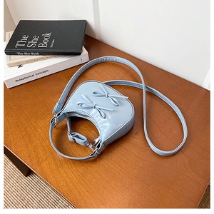 Detail of light blue crescent bag with leather bows and silver adjustable strap
