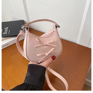 Close-up of pink mini handbag with decorative bows and silver hardware details