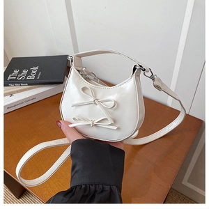 Detail of white moon bag with delicate bows and adjustable strap for women