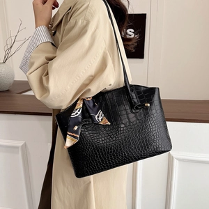Fashionable black crocodile embossed tote bag with elegant silk scarf on shoulder strap